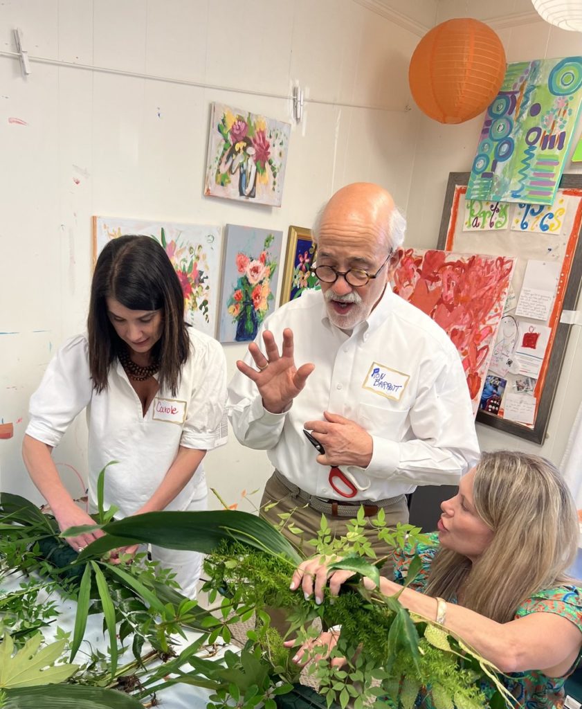 3 people in art room holding greenery