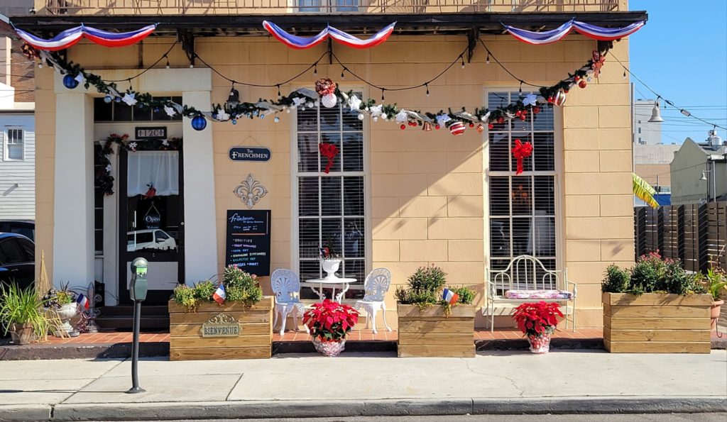 Store front of The Frenchmen decorated for Holiday season with ornaments and poinsettias 