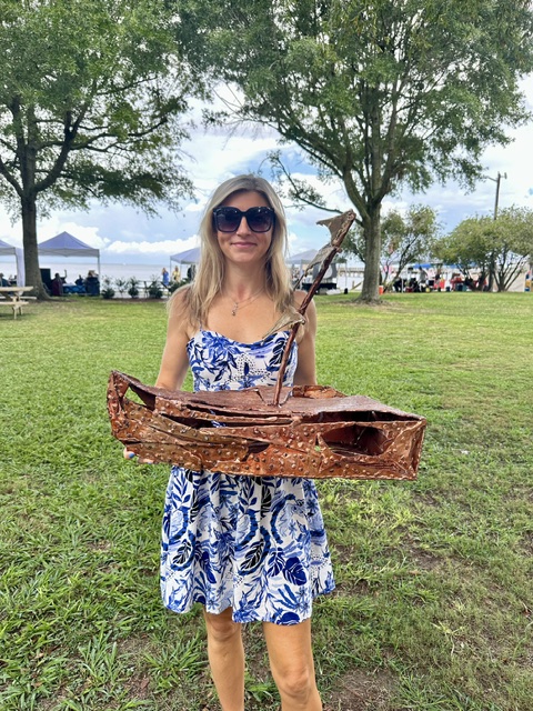 Laura Ledbetter posing with shipwreck sculpture at art festival in Alabama