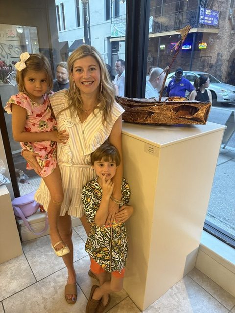 Laura Ledbetter posing with her sculpture and her children at Mobile Arts Council Gallery @Room 1927 