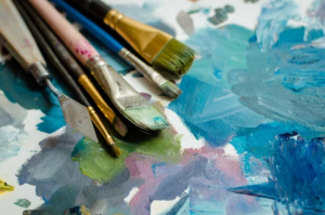 Paintbrushes with blue green and purple watercolor on pallet