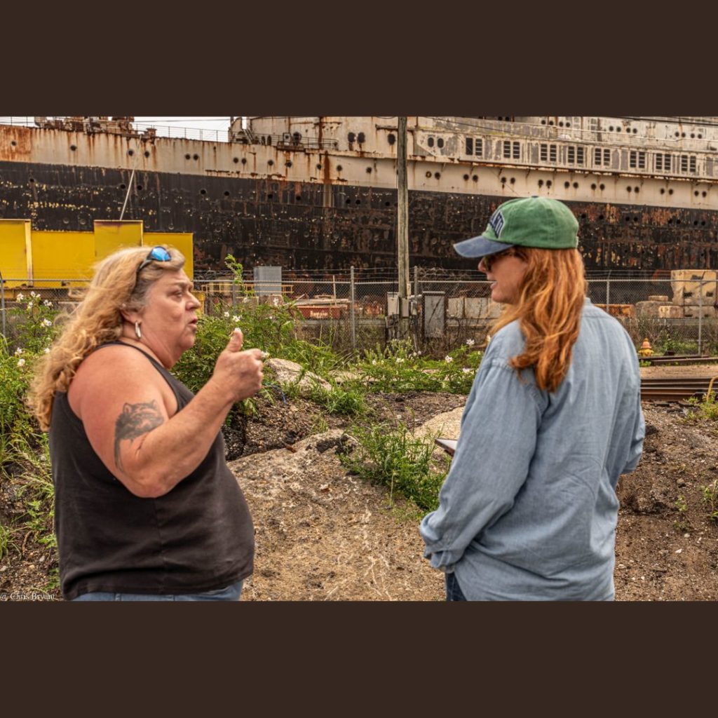 Lynn Oldshue interviewing woman near boat yard